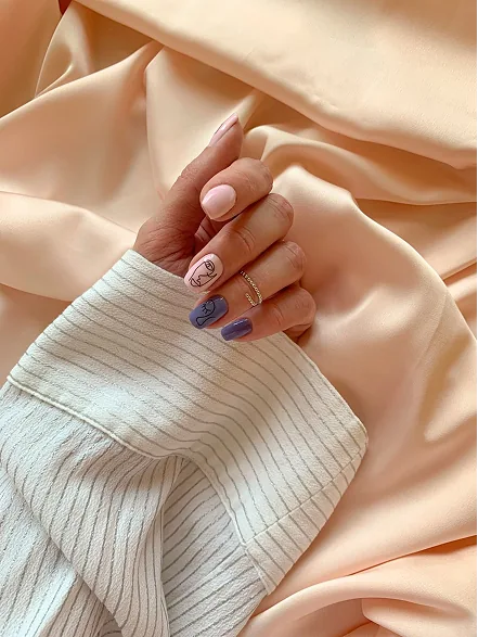 Tony's Nails - Hand with pastel nail art on champagne silk fabric